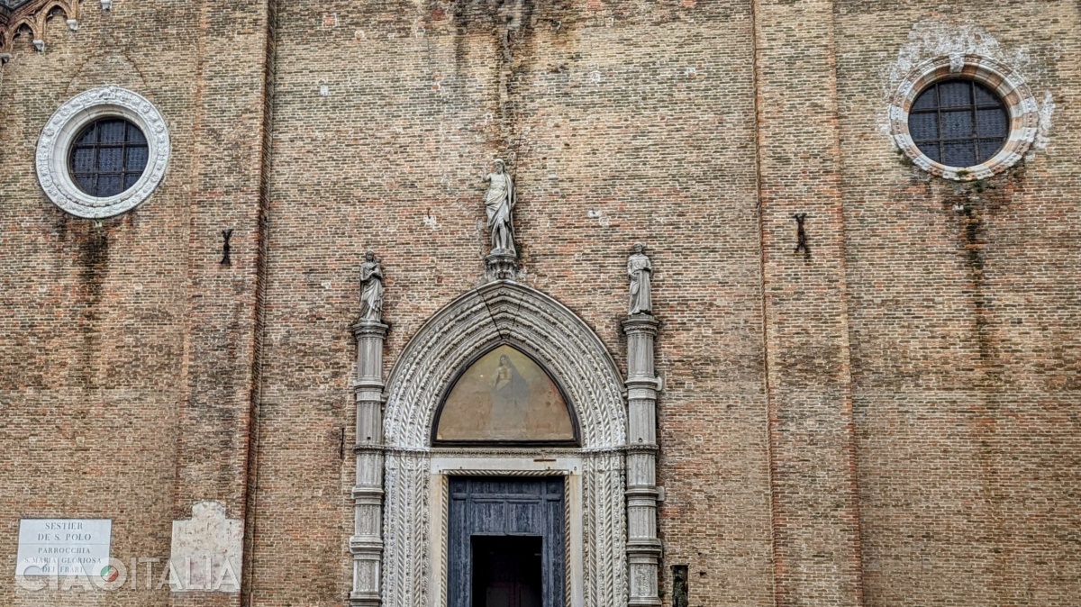 The portal is adorned with three statues, and the side rose windows indicate the position of the similarly named chapels inside the church.
