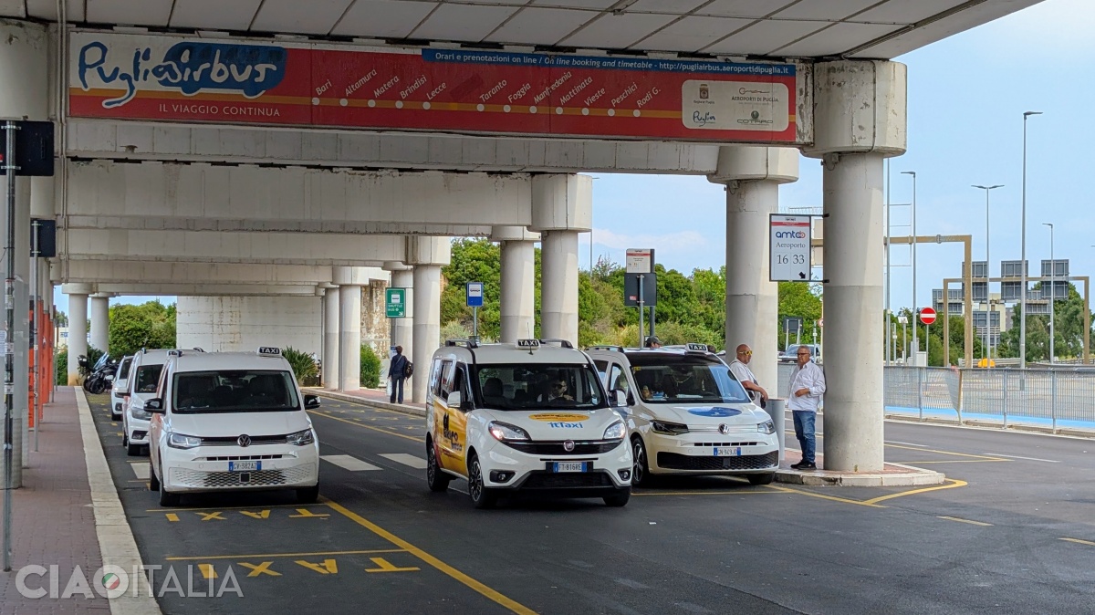 The taxis are waiting in front of the airport.