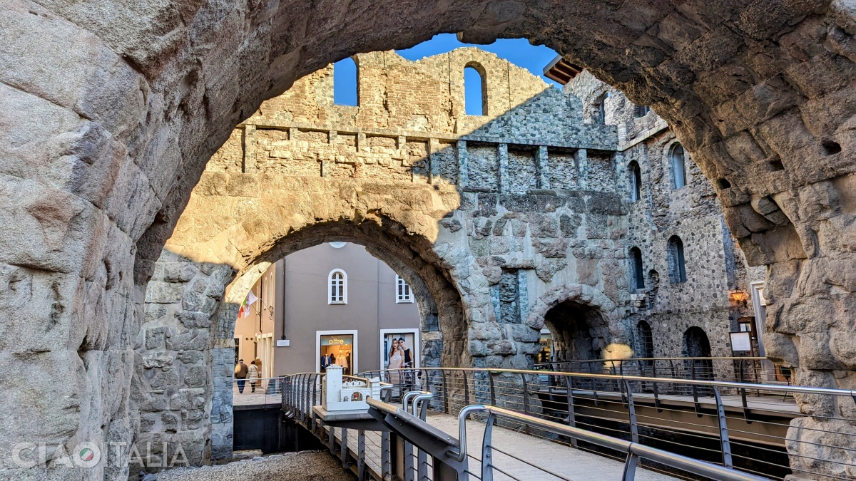 Two parallel arches connected by towers enclose an interior space.