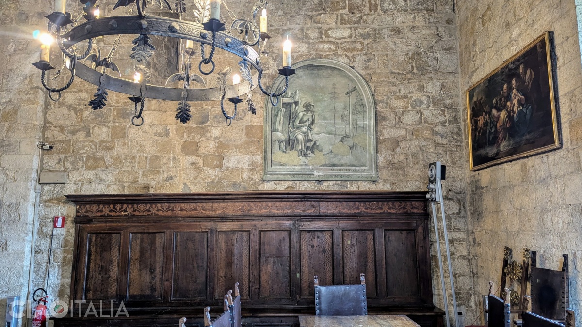 The monochrome fresco to the left of the entrance is attributed to the painter Luca Signorelli.