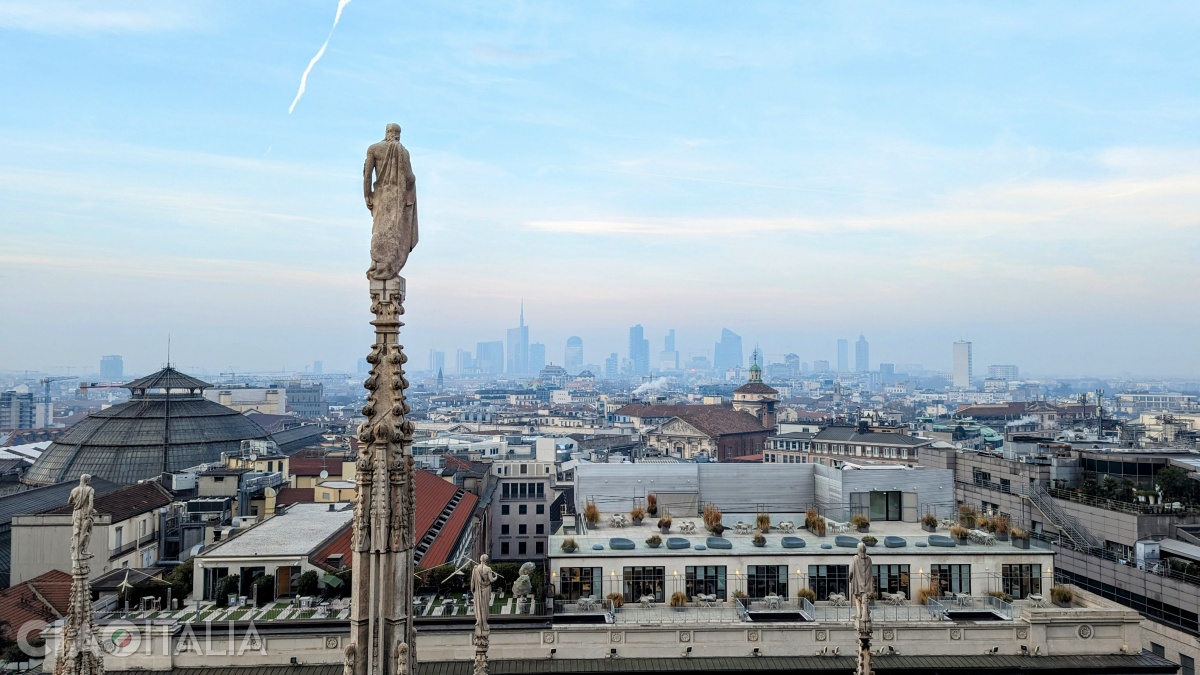 The old statues overlook the modern buildings of the city.