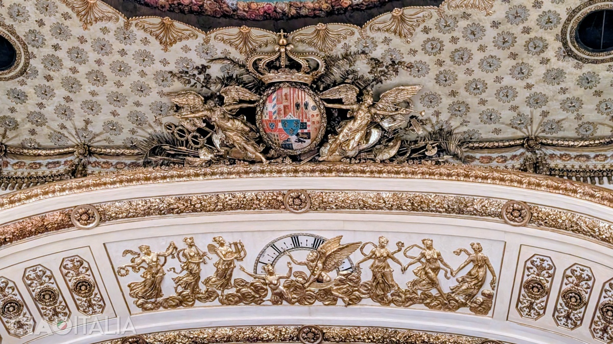 The clock with the rotating dial is located beneath the coat of arms of the House of Bourbon.