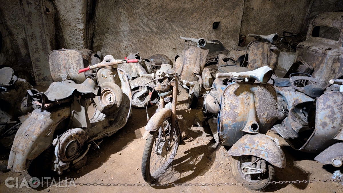In addition to cars, you can also see several old motorcycles and scooters.