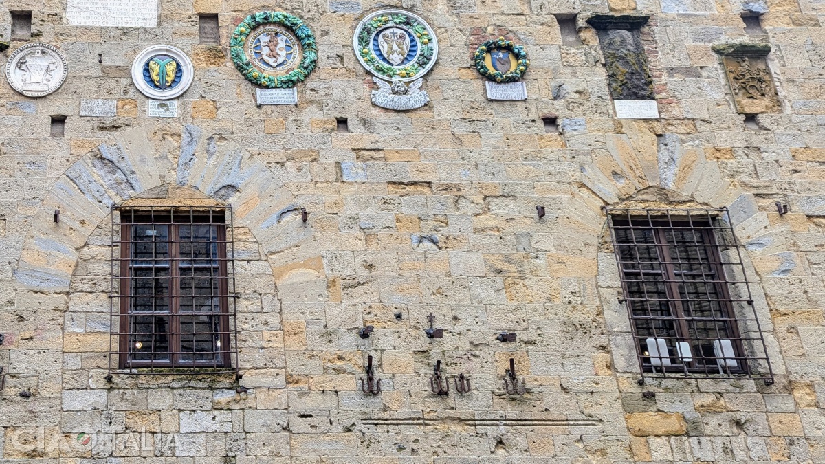 Some of the coats of arms on the façade were made in the workshop of the Della Robbia artists. Below, between the windows, the city's unit of measurement can still be seen.