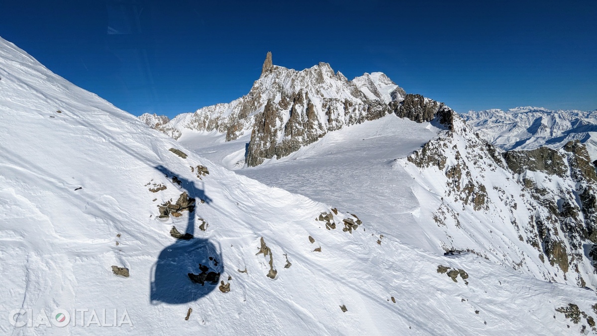 The shadow of the cable car is cast on the snow.