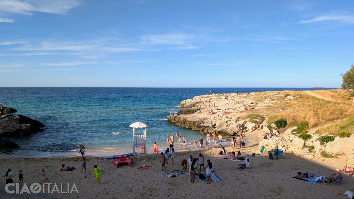 The beach is also small, sandy, and surrounded by rocky cliffs.